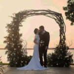 Bride and groom under circle driftwood wedding arch